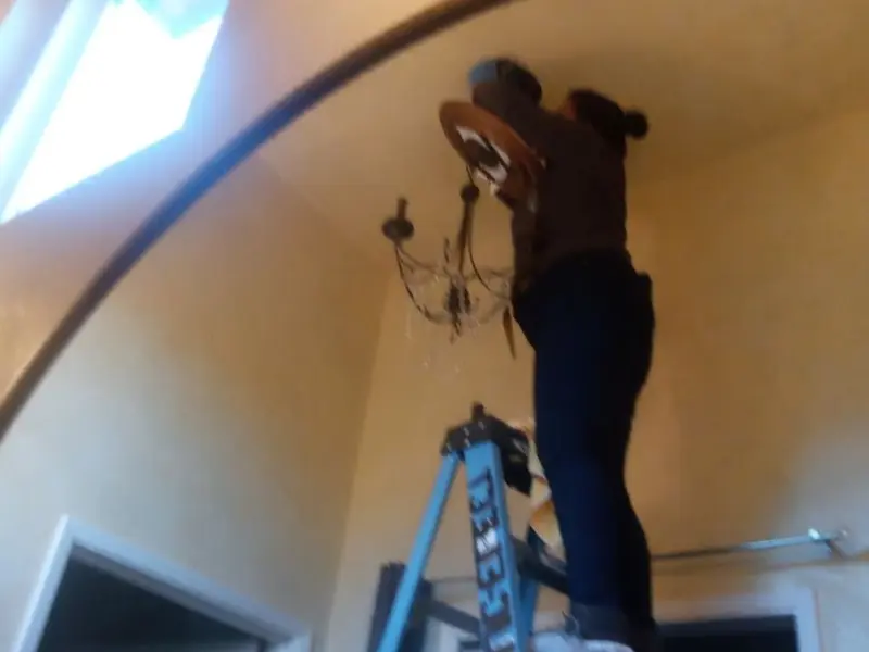 Electrician installing a chandelier in a Norwich residence